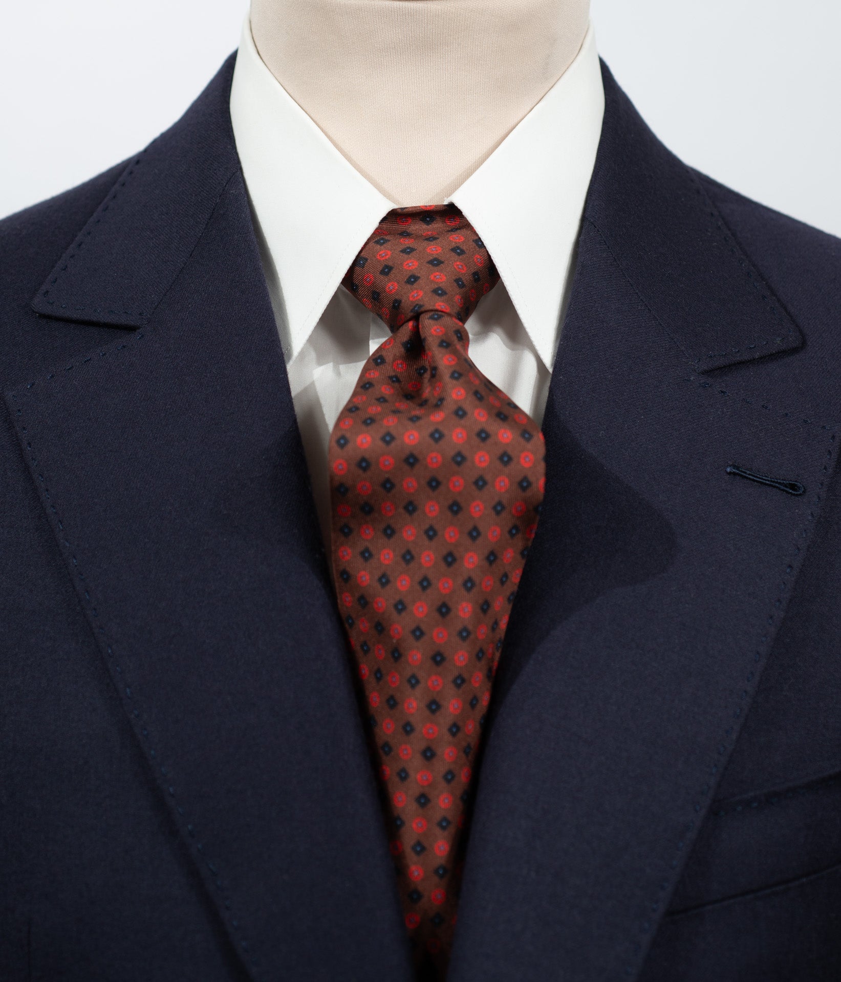 Cravate en twill 100 % soie, ornée d’un motif de fleurs bleu nuit et rouge sur fond marron