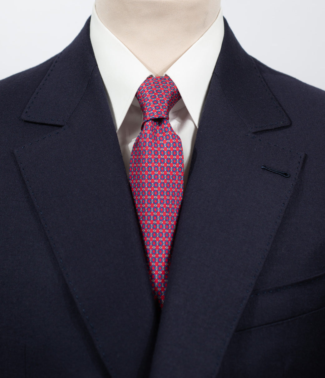 Cravate en twill 100% soie, ornée d'un motif géométrique bleu sur fond rouge