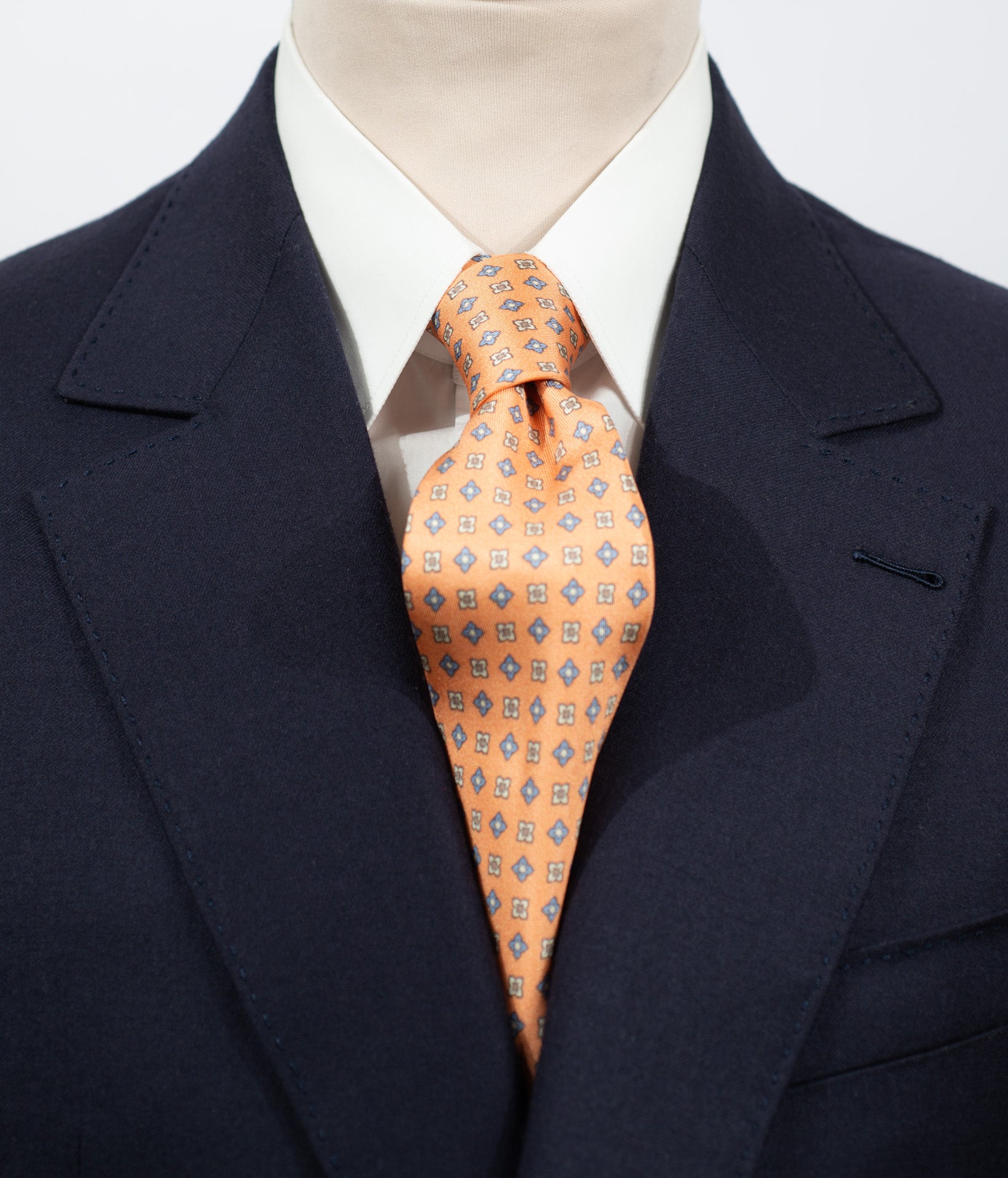 Cravate en twill 100% soie, ornée d'un motif de fleurs bleues et blanches sur fond orange