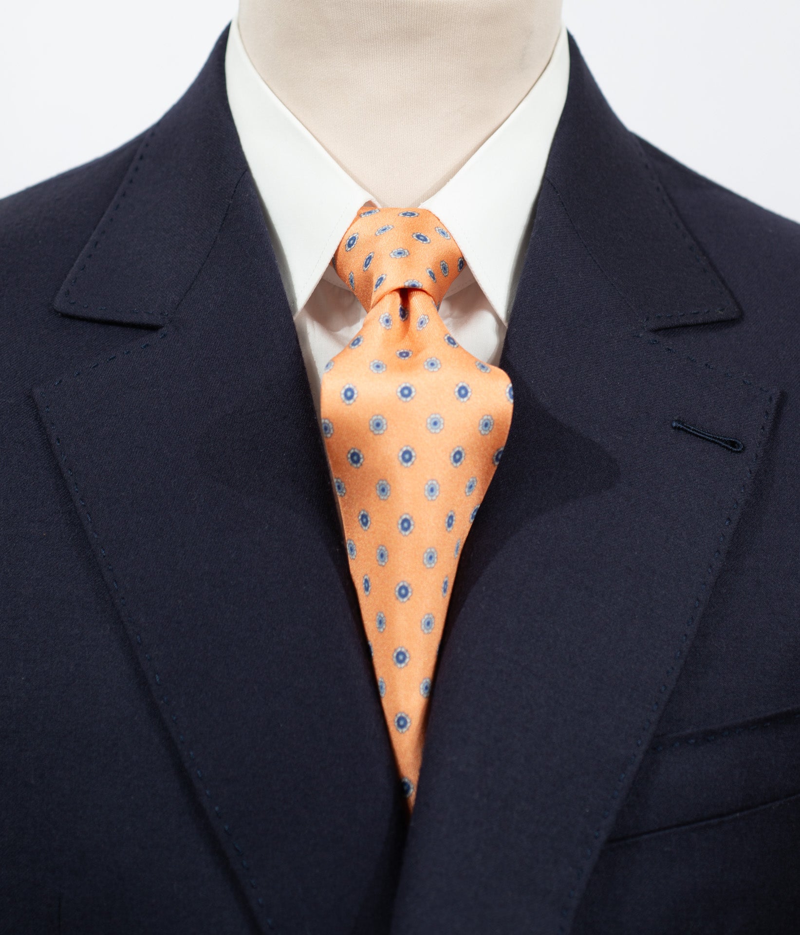 Cravate en twill 100% soie, ornée d'un motif de fleurs bleues sur fond orange