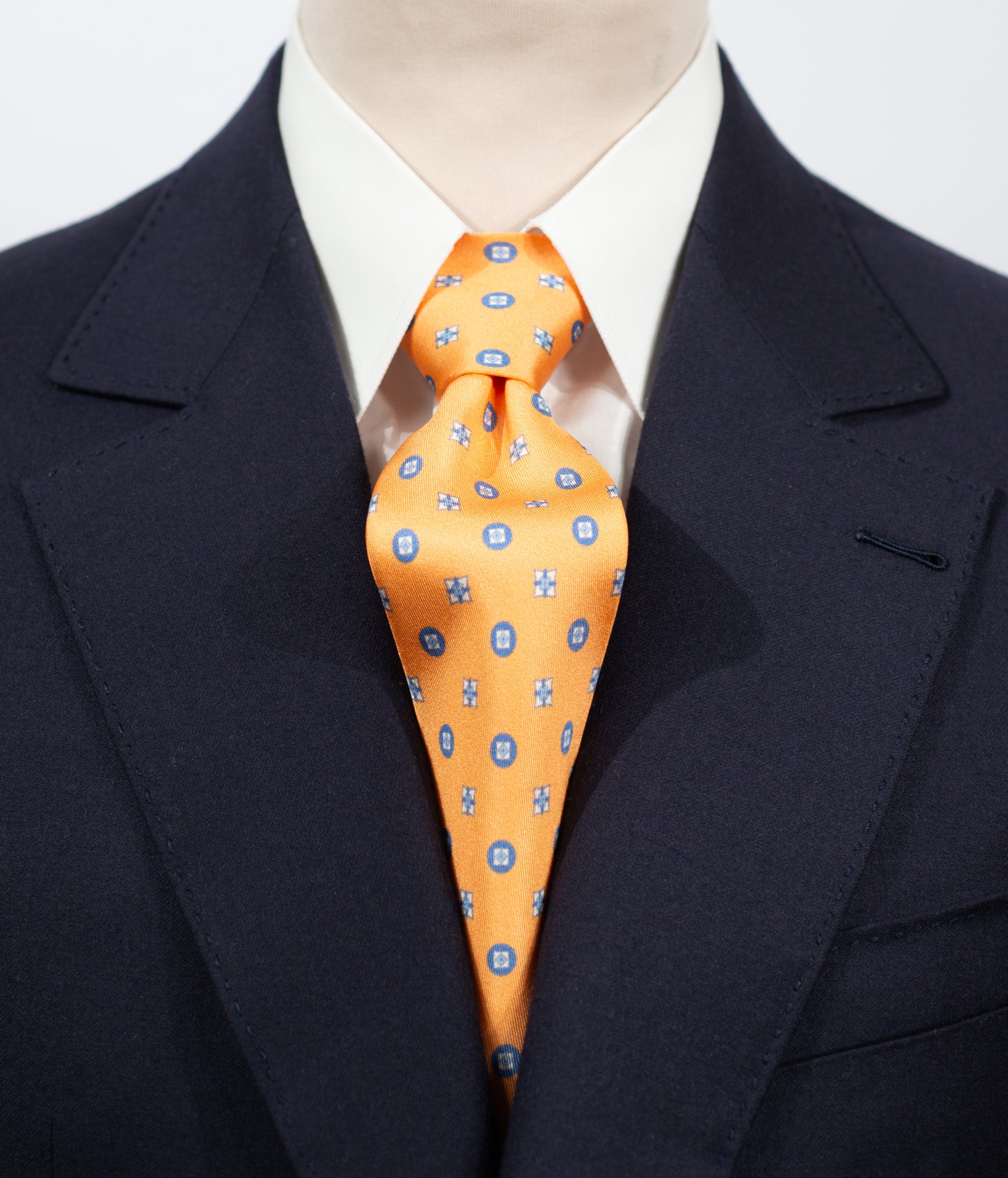 Cravate en twill 100% soie, ornée d'un motif de fleurs bleues sur fond orange