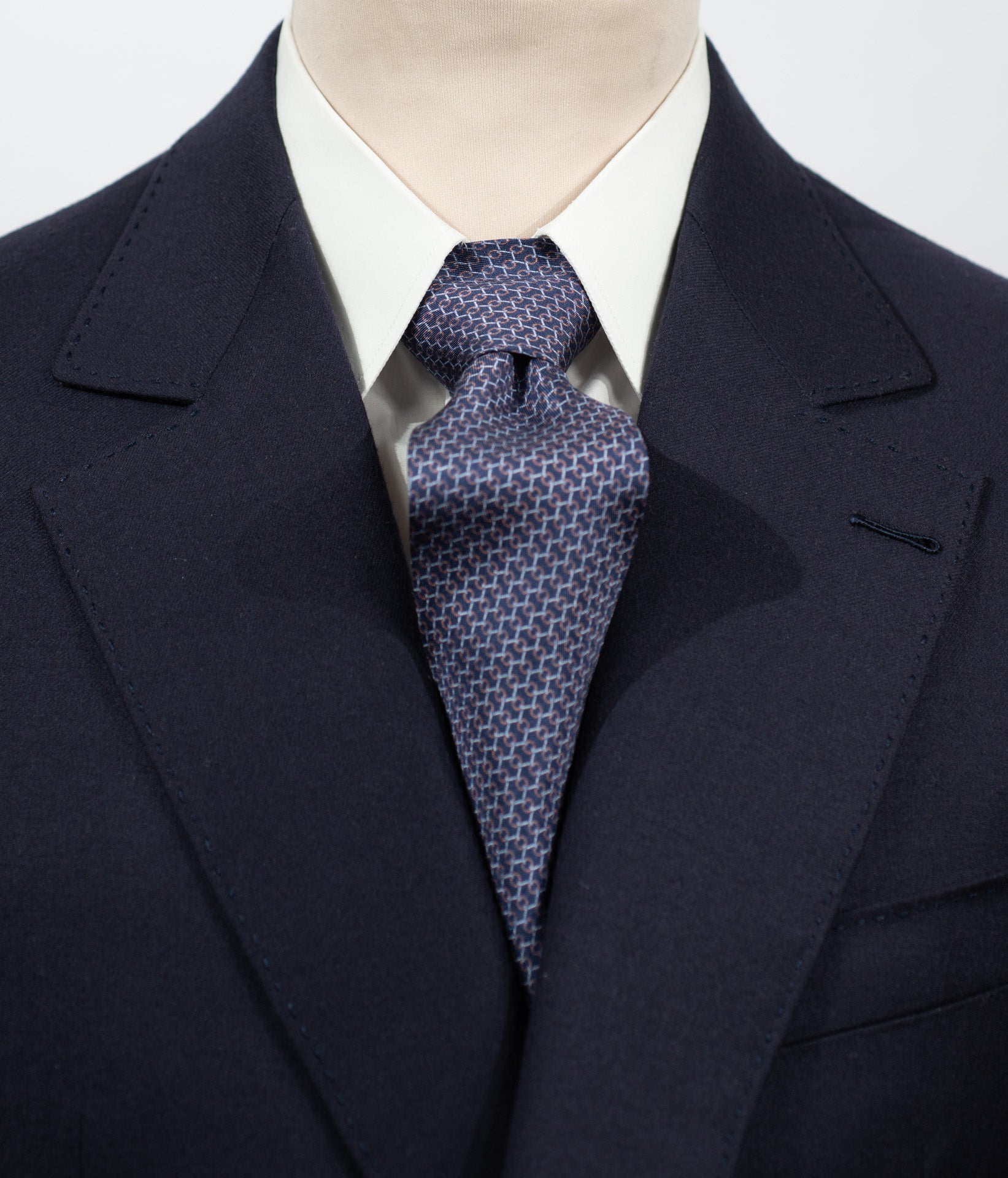 Cravate en twill 100% soie, ornée d'un motif géométrique orange et blanc sur fond bleu