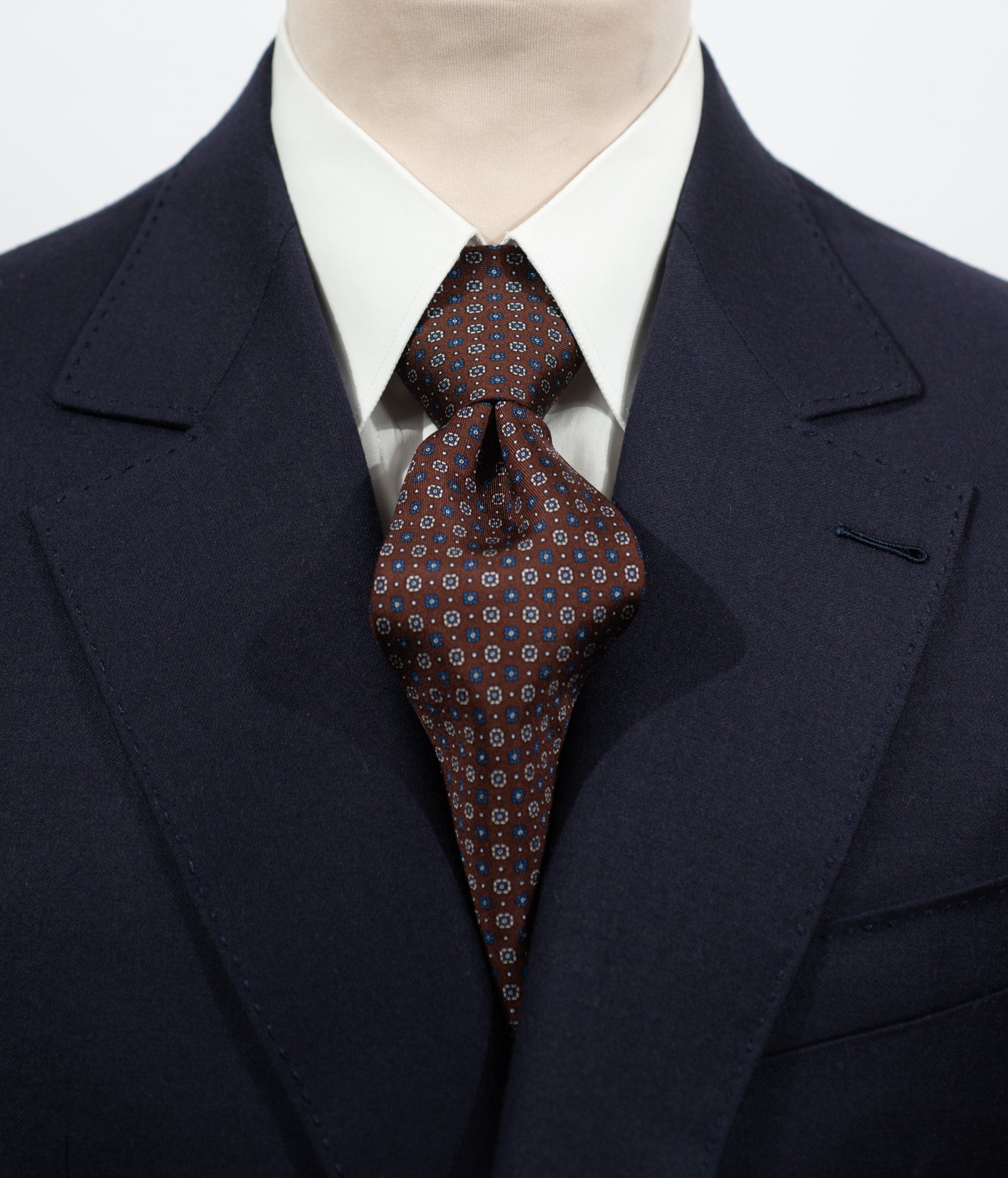 Cravate en twill 100% soie, ornée d'un motif de fleurs bleues et blanches sur fond marron