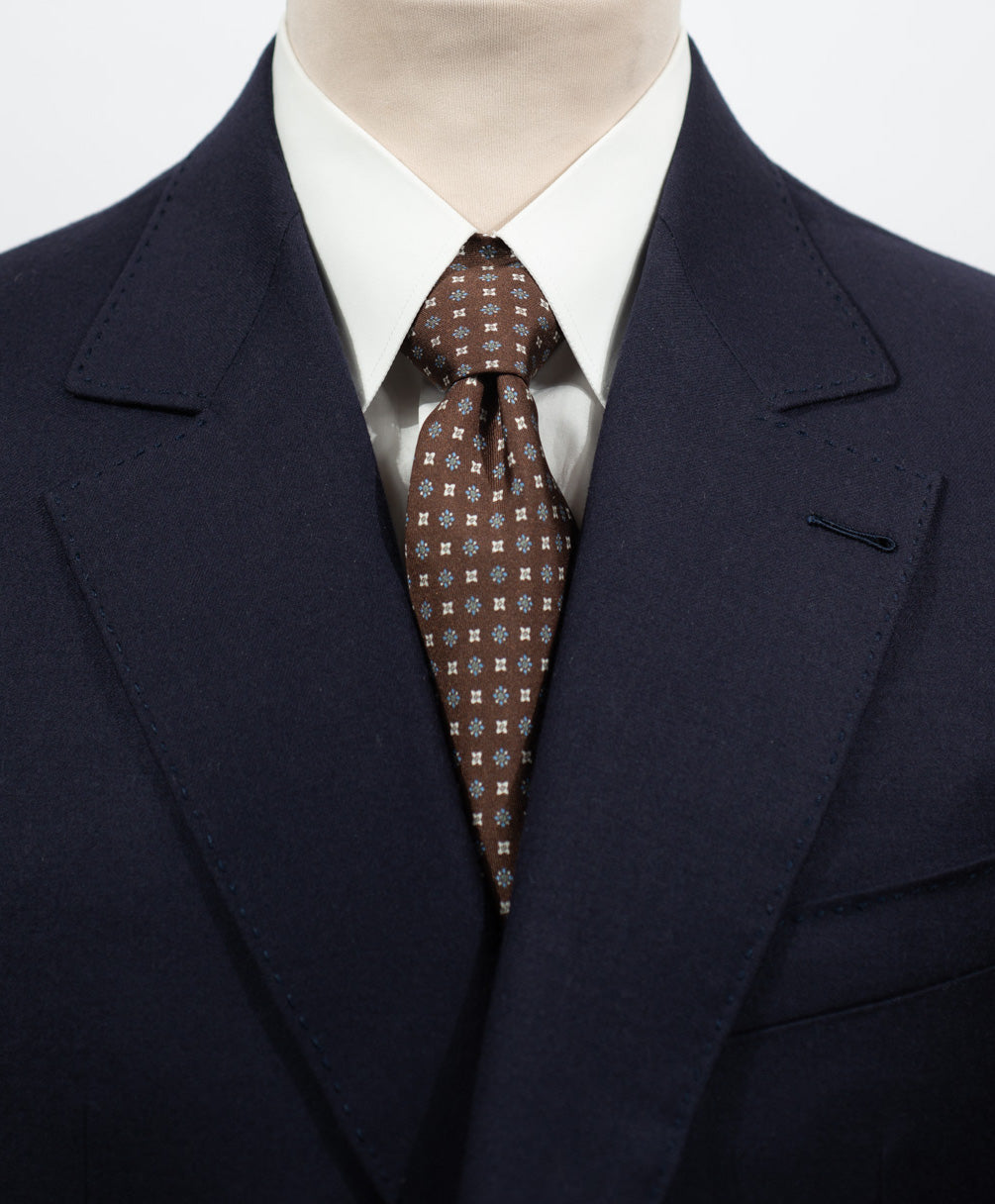 Cravate en twill 100% soie, ornée d'un motif de fleurs bleues et blanches sur fond marron