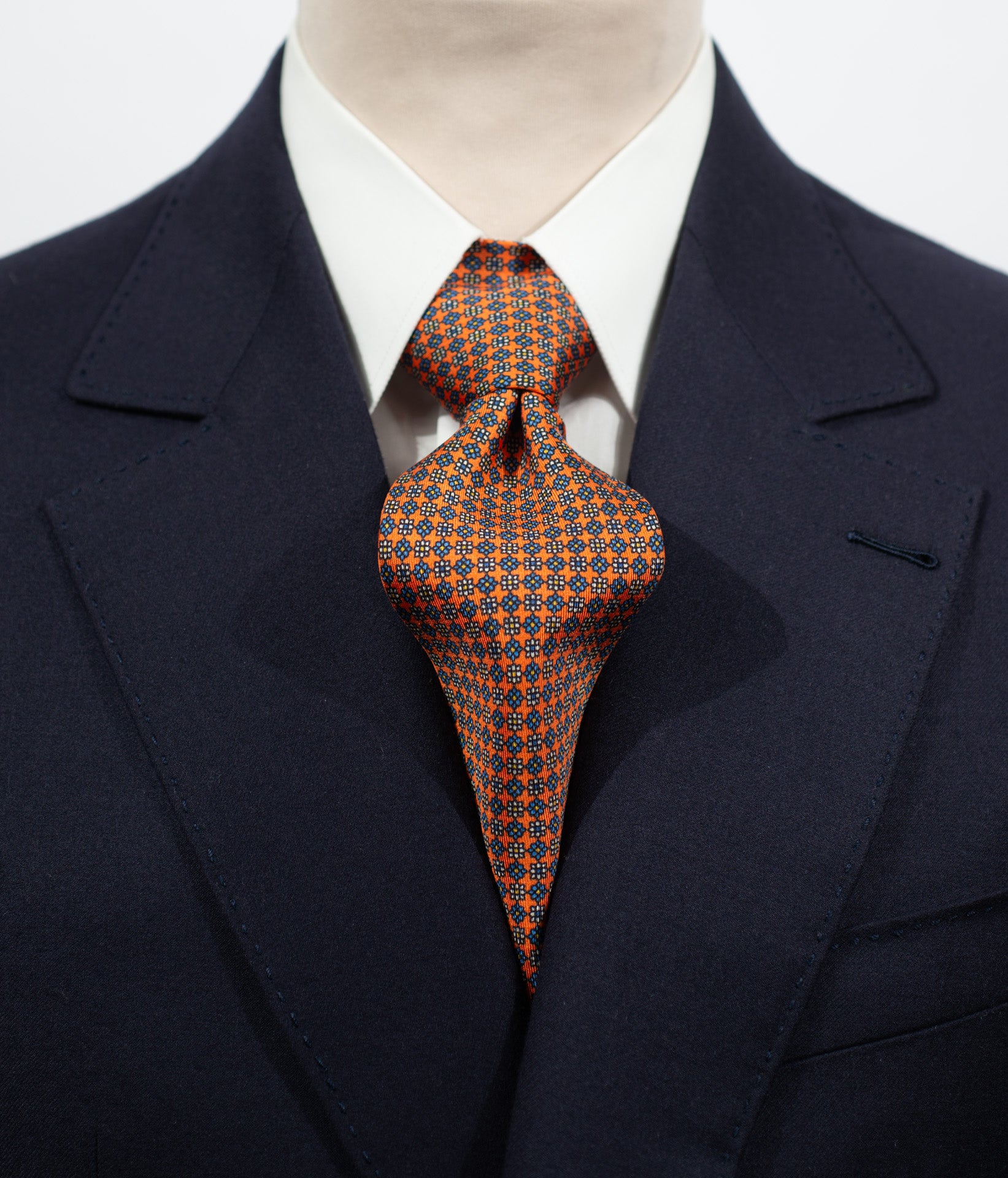 Cravate en twill 100% soie, ornée d'un motif de fleurs bleues et blanches sur fond orange