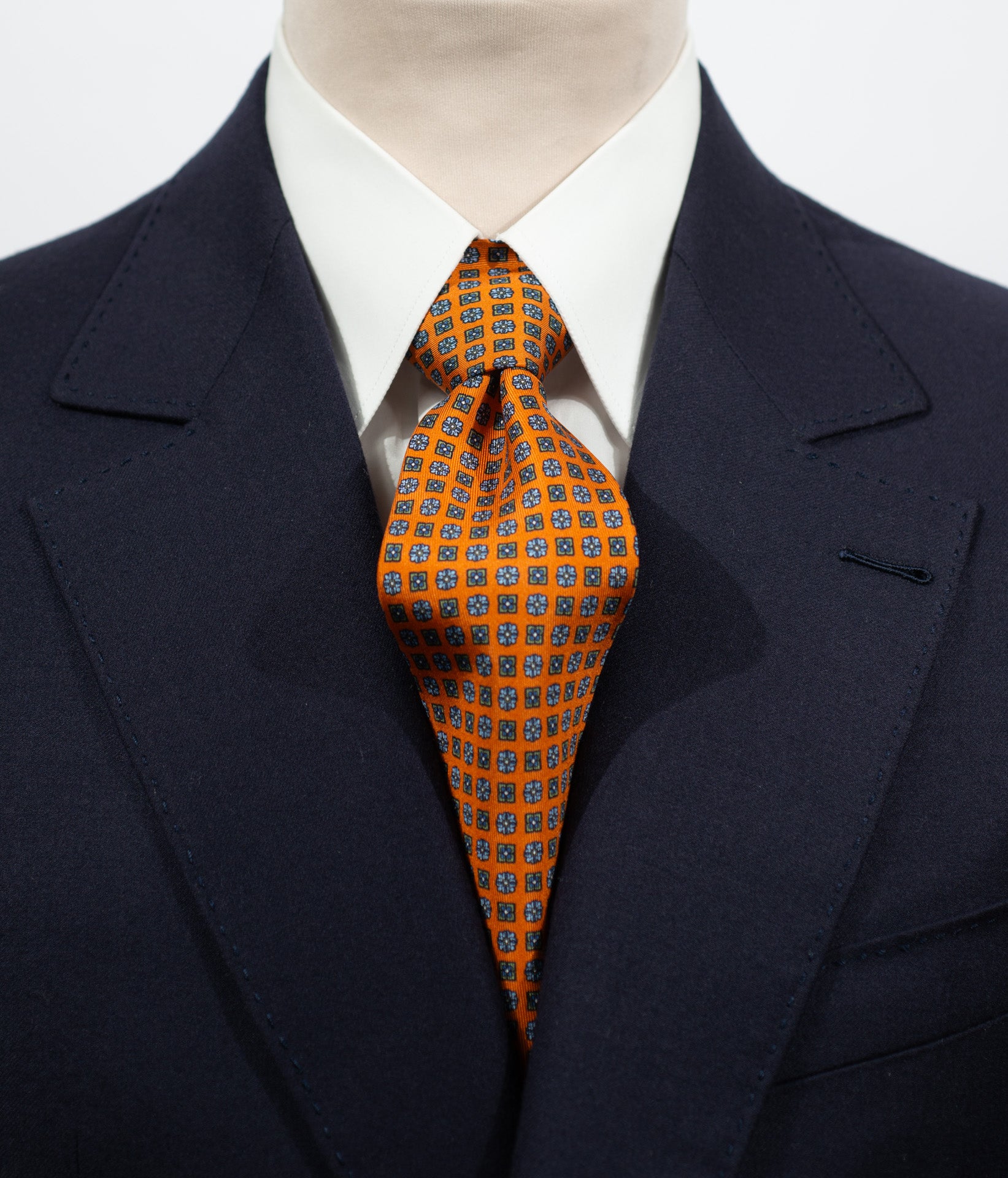 Cravate en twill 100% soie, ornée d'un motif de fleurs bleues sur fond orange