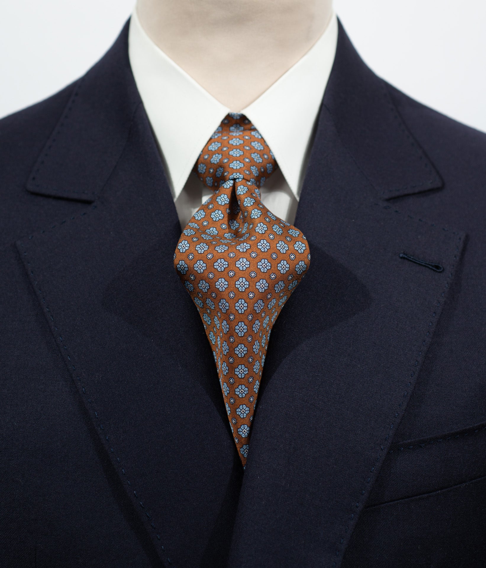 Cravate en twill 100% soie, ornée d'un motif de fleurs bleues sur fond marron