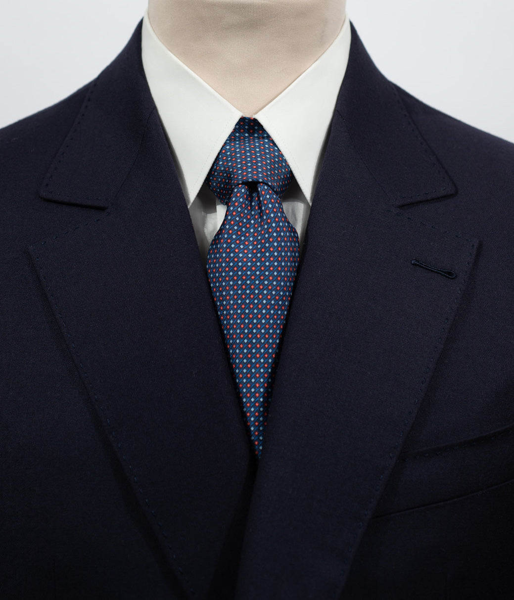 Cravate en twill 100% soie, ornée d'un motif géométrique rouge et bleu sur fond bleu