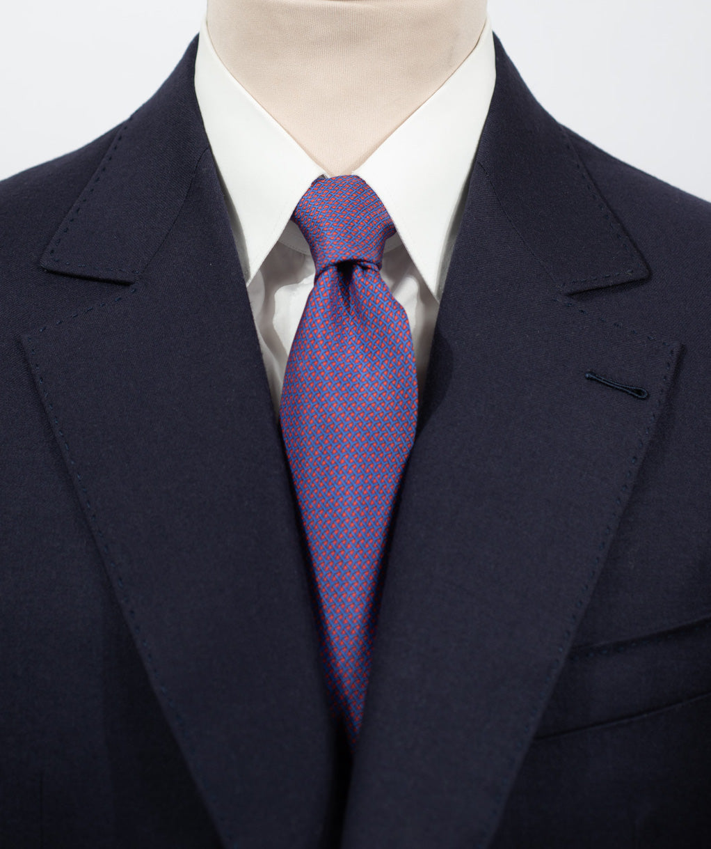 Cravate en twill 100% soie, ornée d'un motif géométrique bleu sur fond rouge